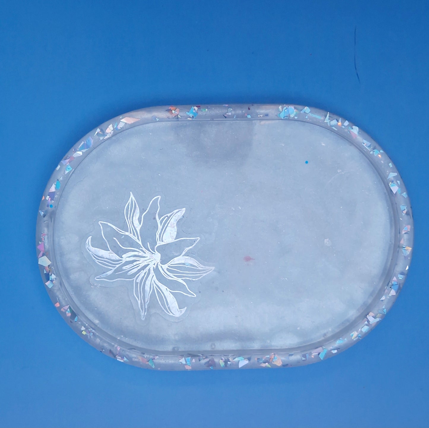 Vista superior de bandeja floral em resina epóxi branca com purpurinas holográficas no rebordo