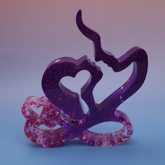 Escultura decorativa em resina epóxi representando casal com coração, em tons de roxo com brilho e detalhes em folhas de ouro rosa, peça artesanal contemporânea.
