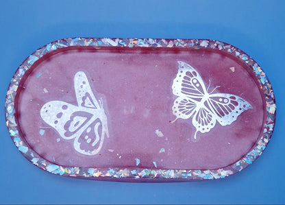 Bandeja decorativa oval em resina epóxi rosa com borboletas brancas e glitters holográficos, vista superior