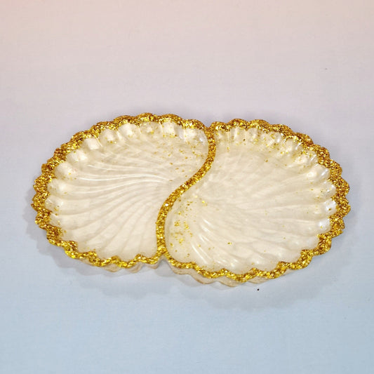 Taça decorativa Twin Shells em resina clara, com formato de conchas duplas, acabamento perolado e bordas com efeito dourado texturizado, vista superior.