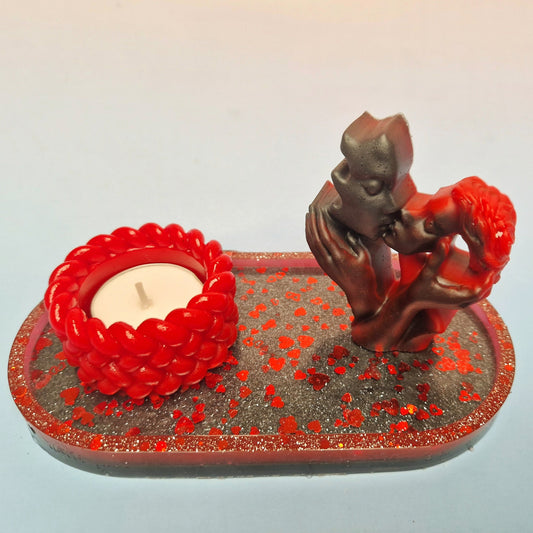 Escultura de casal em resina epóxi com castiçal vermelho texturizado, sobre tabuleiro preto com corações