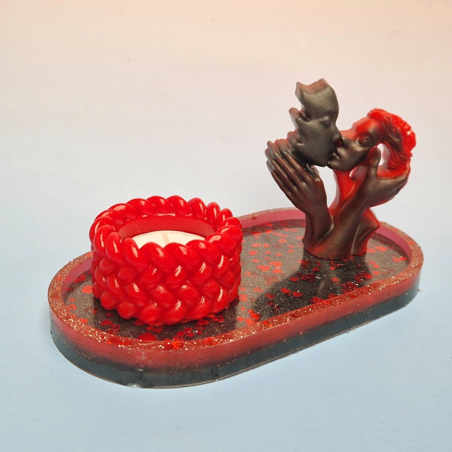 Escultura de casal em resina epóxi com castiçal vermelho texturizado, sobre tabuleiro preto com corações