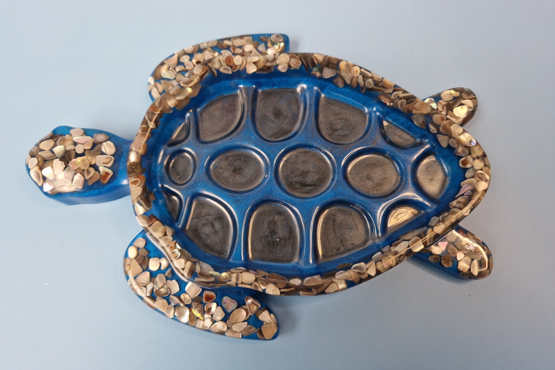 Tartaruga decorativa azul em resina epóxi com conchas naturais incrustadas, vista superior da carapaça texturizada.