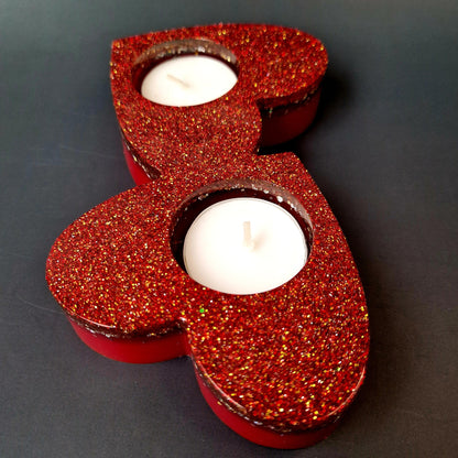 Porta-velas duplo em forma de coração em resina epóxi vermelho intenso com glitter dourado, vista lateral destacando o relevo e acabamento artesanal.