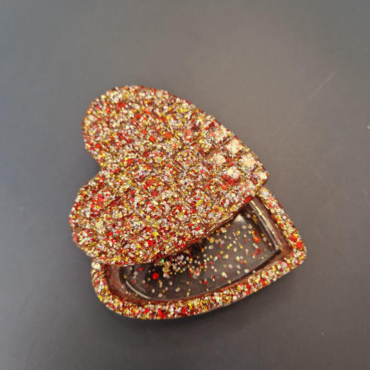 Caixa decorativa em resina epóxi em formato de coração, com glitter vermelho, dourado e acabamento brilhante artesanal.