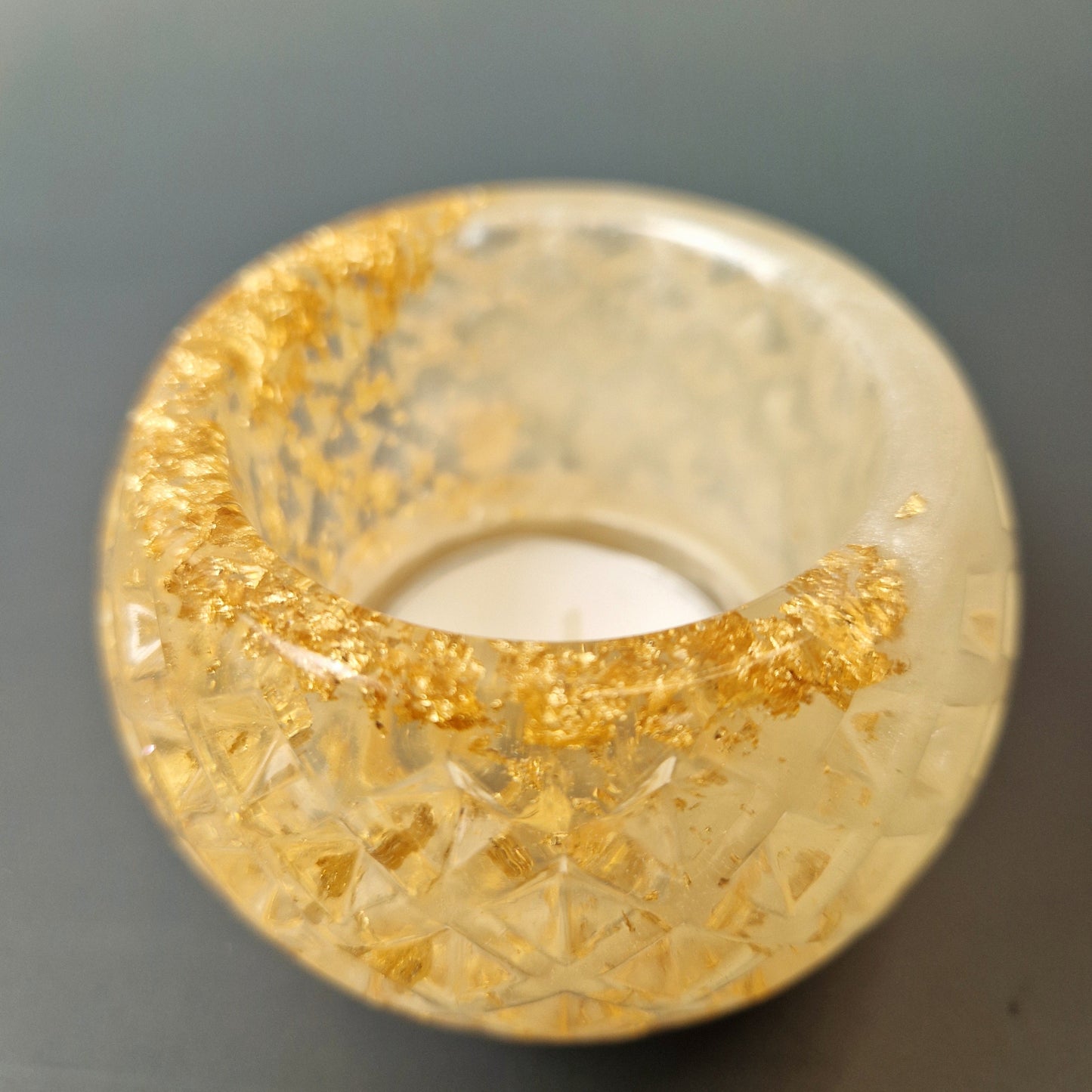 Porta-velas artesanal em resina com textura geométrica e partículas douradas no interior, vista lateral