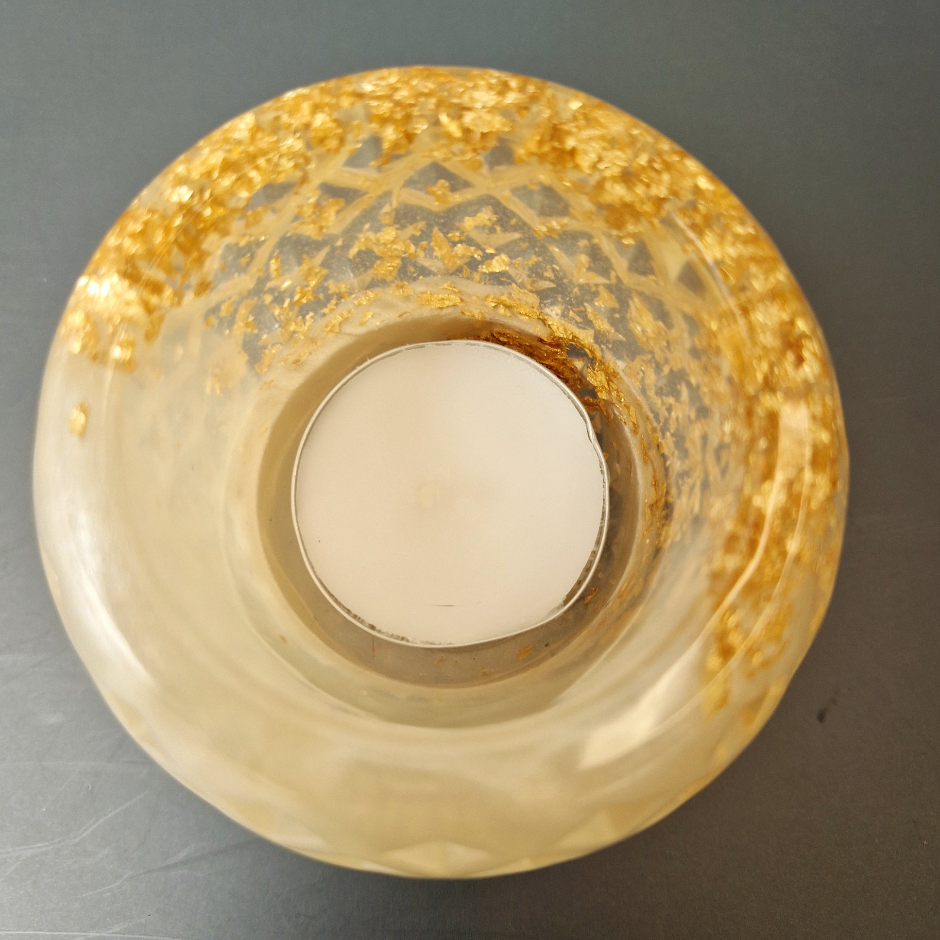 Porta-velas decorativo em resina translúcida com efeito perolado e folha dourada, vista superior com vela no centro