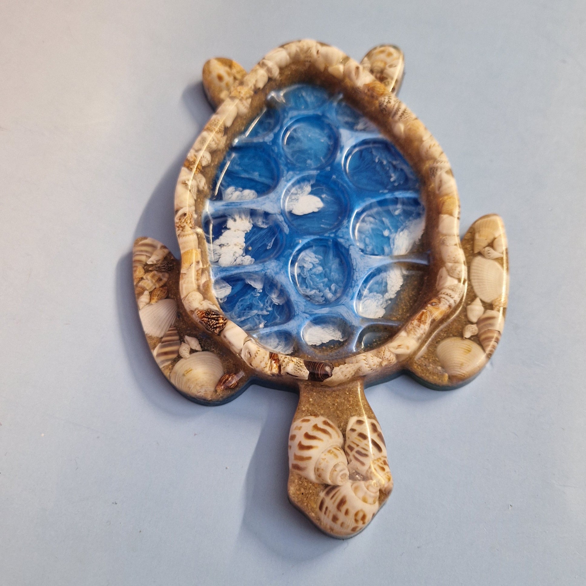 Detalhe do prato tartaruga em resina epoxy com efeito água azul e textura brilhante