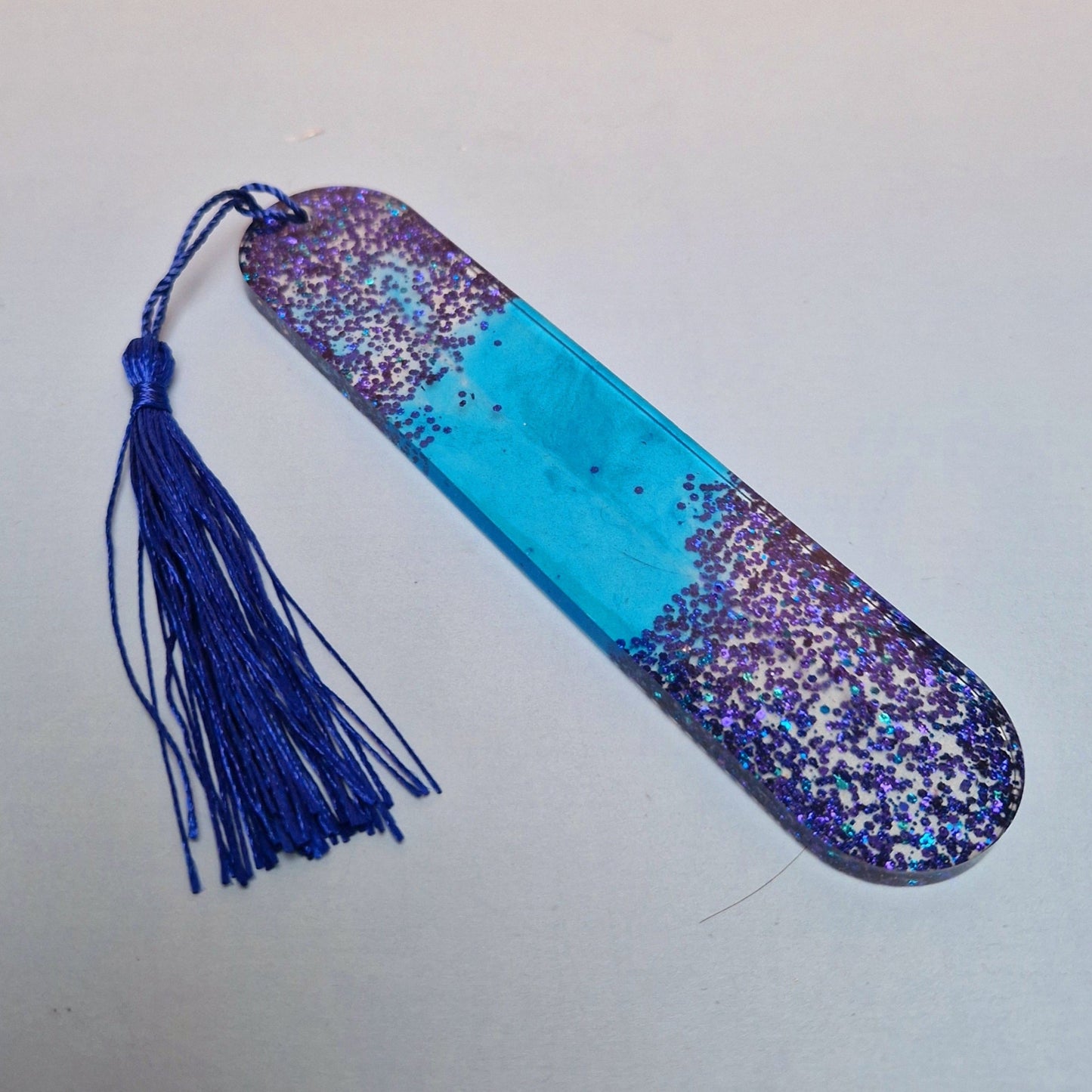 Marca-páginas artesanal em resina epóxi azul translúcido com purpurinas holográficas e tassel azul