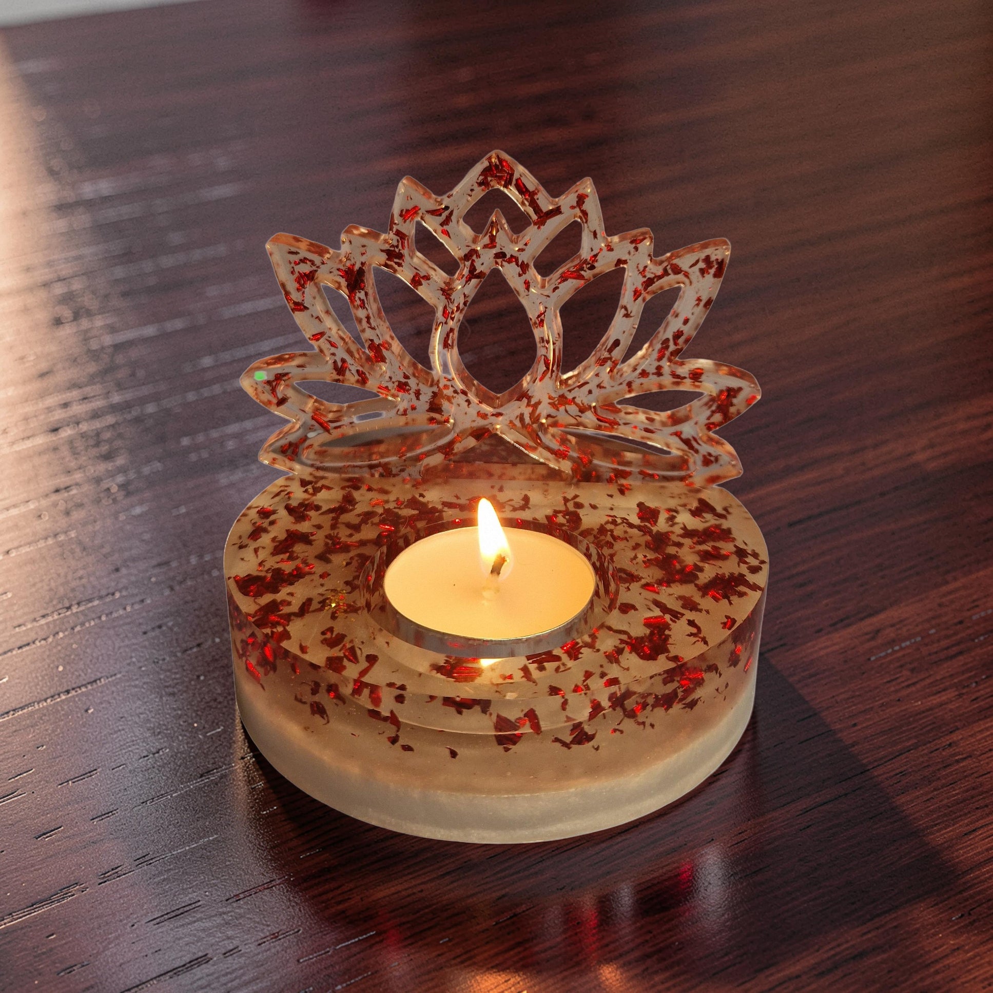 Suporte decorativo em resina com reflexos de folhas metálicas vermelhas sob a luz de uma chama.