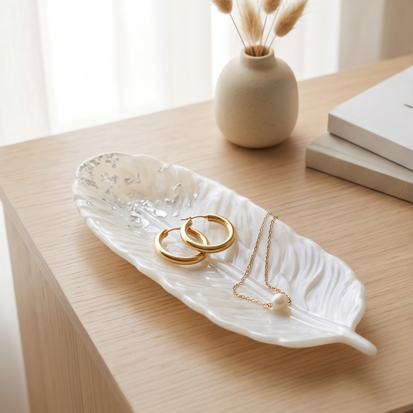 Prato decorativo em forma de pena branco perlado com folha de prata, feito à mão em resina epóxi, ideal para organizar joias e acessórios.