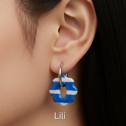 Brincos intercambiáveis Sweet Art com pendentes Lili em argila polimérica azul e branca às riscas, usados com argolas.
